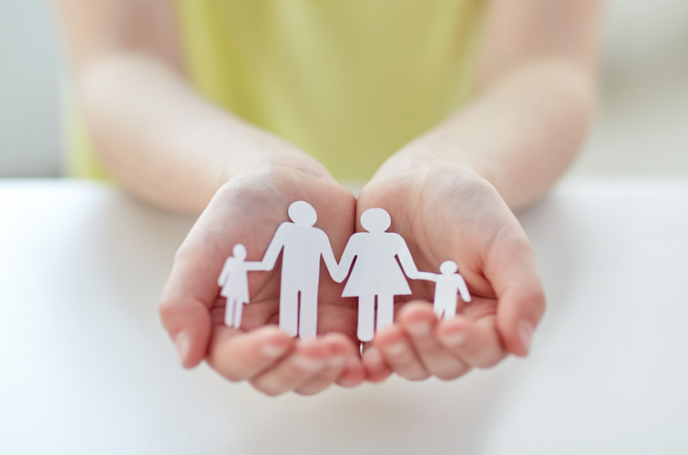 people, charity and care concept – close up of child hands holding paper family cutout at home