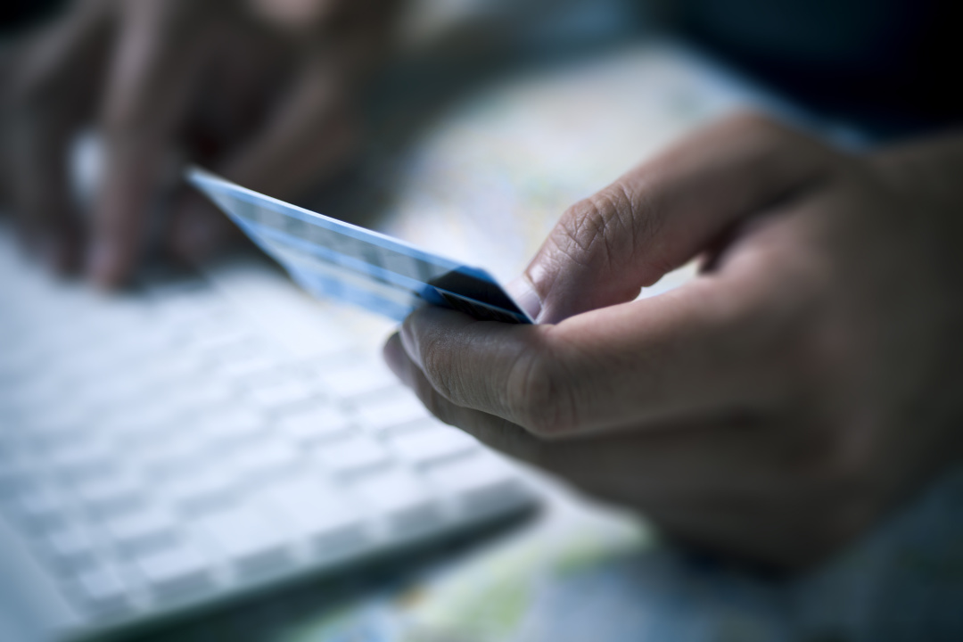 closeup of a young caucasian man using a credit card to buy online, using his computer